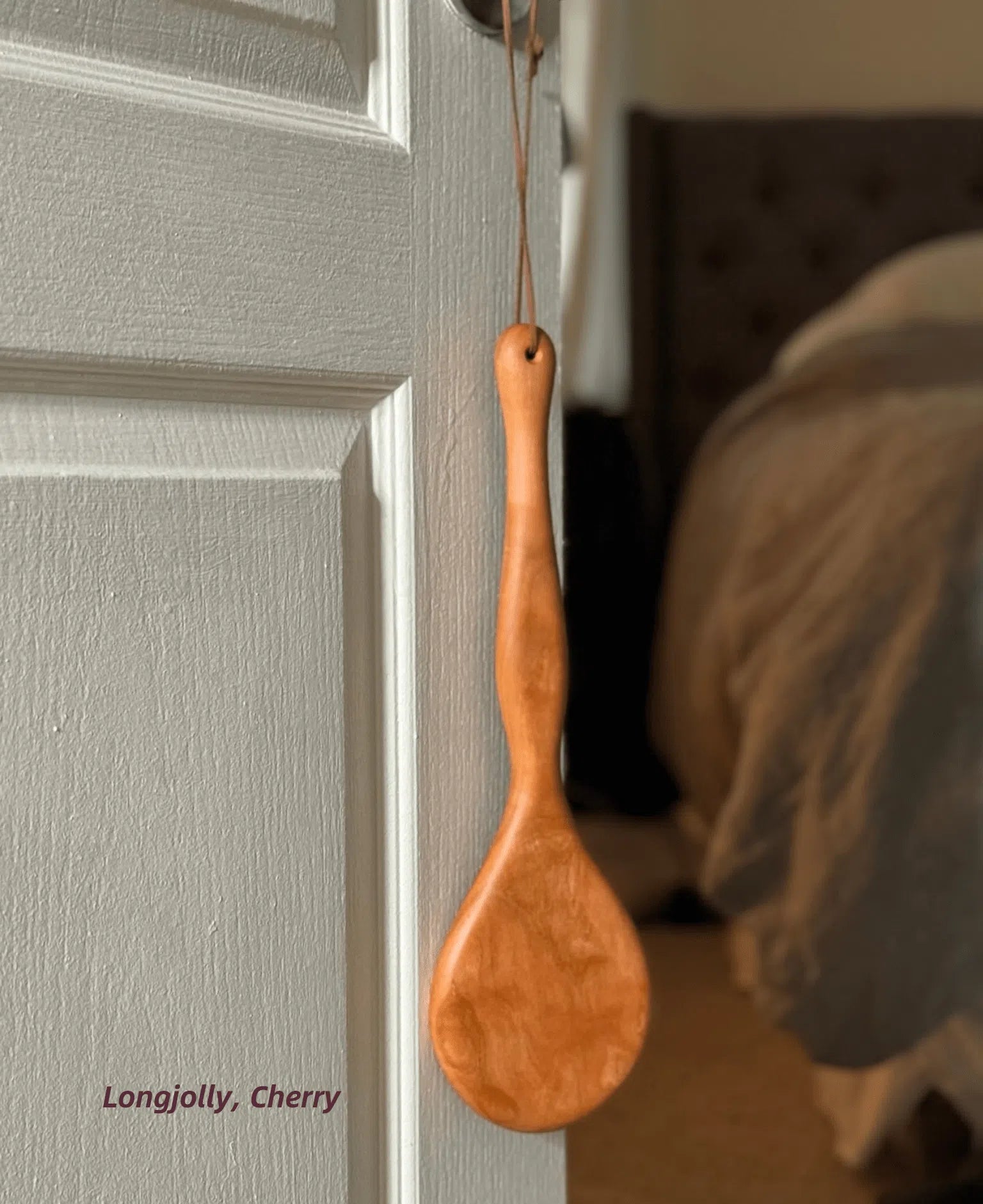 LRS Toys Longjolly spanking paddle pictured in Cherry and hanging from a doorknob